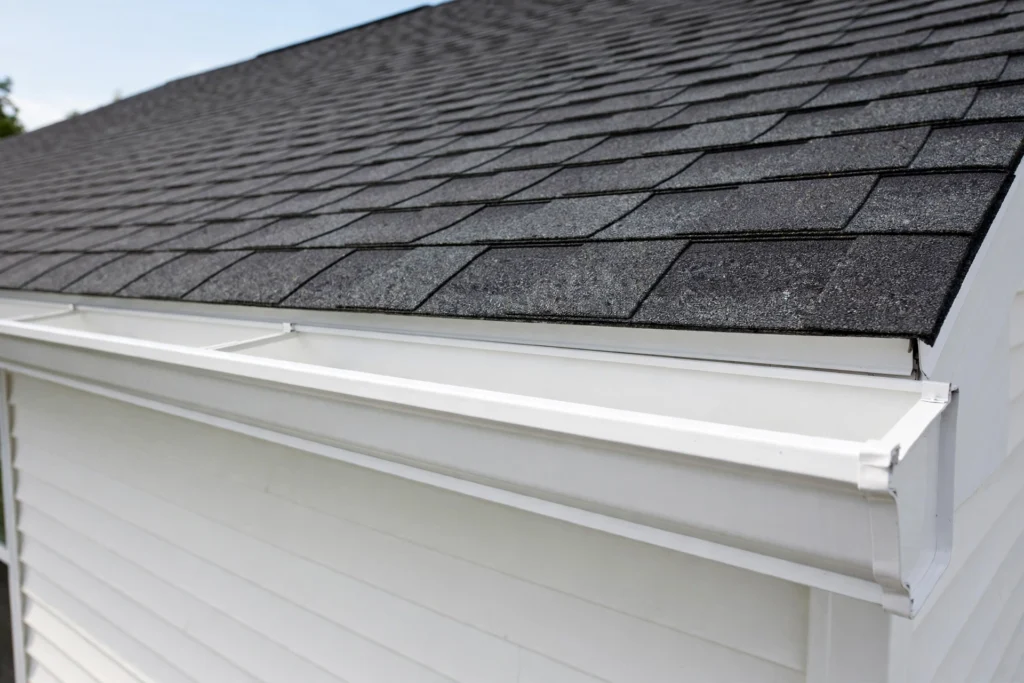 Spotlessly clean white gutter along a shingle roofline after professional cleaning